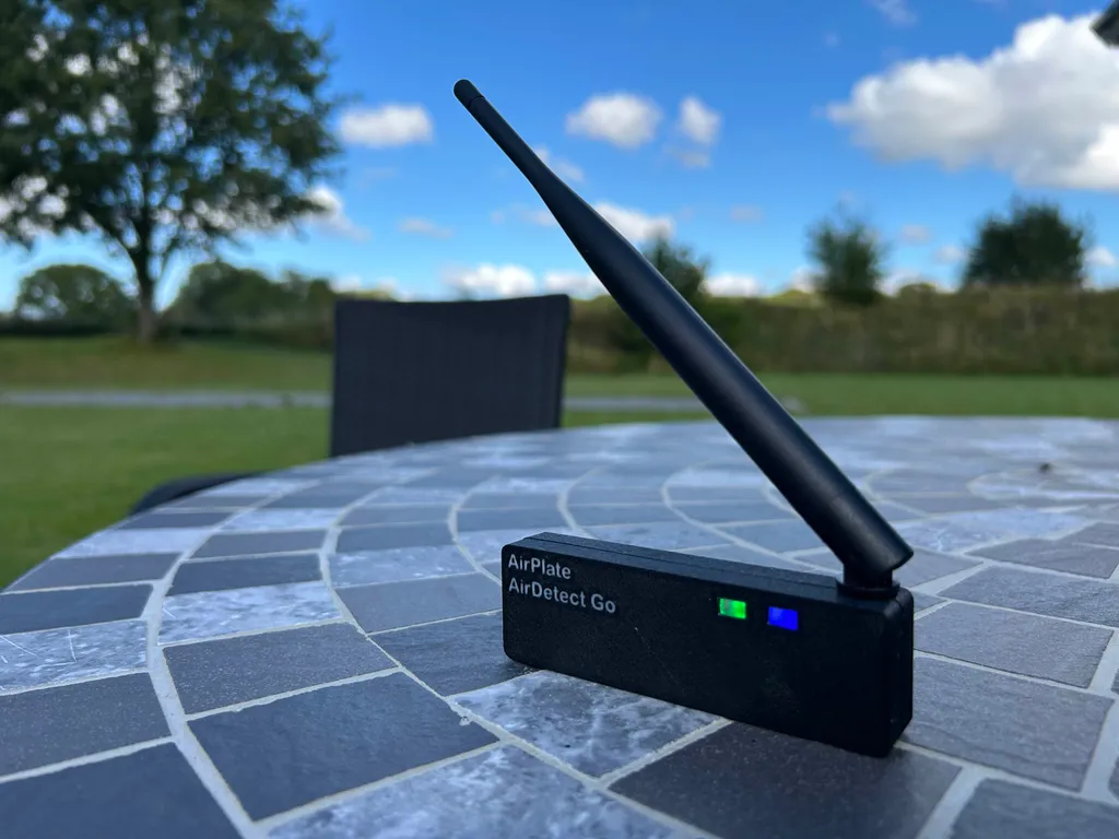 AirDetect Go handheld drone detector with its antenna up, on an outdoor table